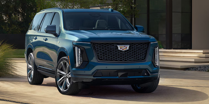 Blue Cadillac XT6 parked outside a modern building with a clean, minimalist background.
