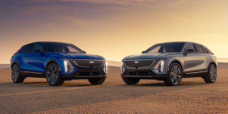 Two Cadillac LYRIQ electric SUVs parked in desert landscape at sunset
