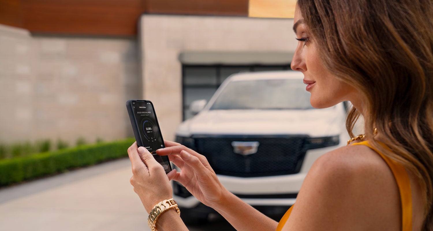 lady checking her mobile with a Cadillac vehicle background | Wiesner of Huntsville in Huntsville TX